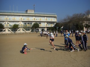 長なわとびを低い位置に固定し，跳ぶ場所の確認と練習をする子どもたち(10:15)